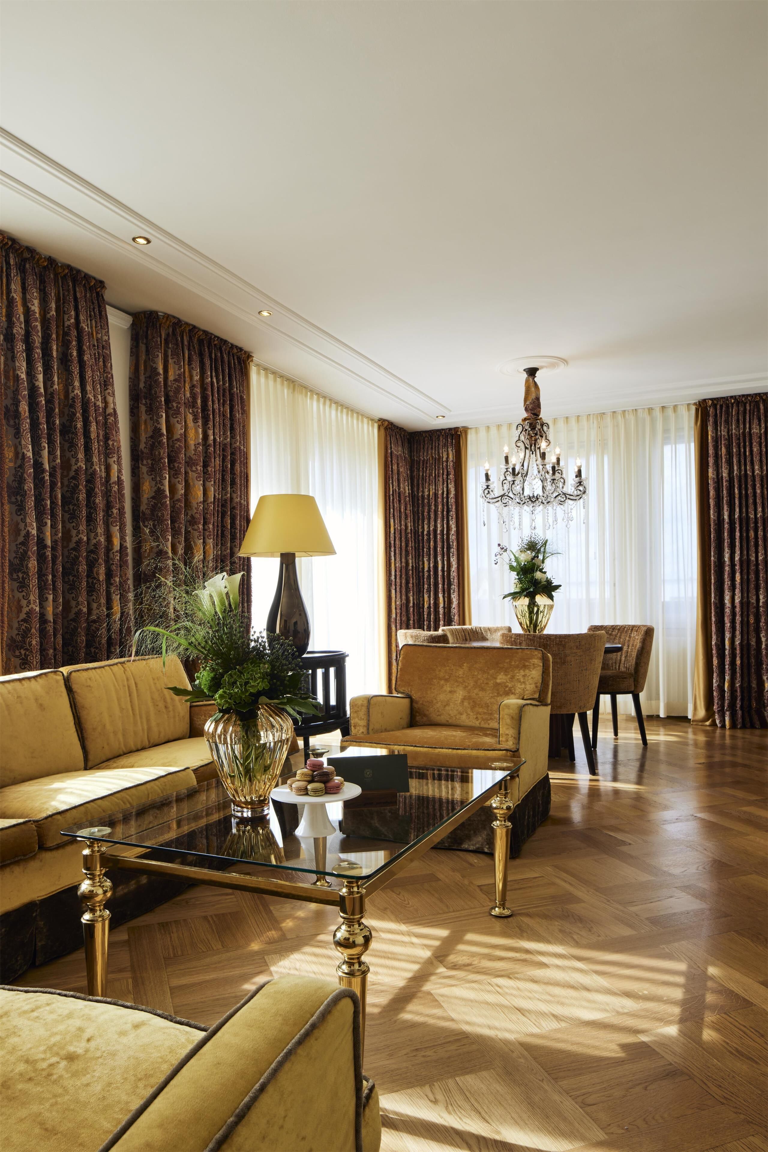 Een ruime woonkamer met een bank, fauteuils, een salontafel en een eethoek.
