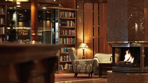 A cozy lobby with a fireplace, a bookshelf, and a seating area. - Parkhotel Gütersloh (Guetersloh)