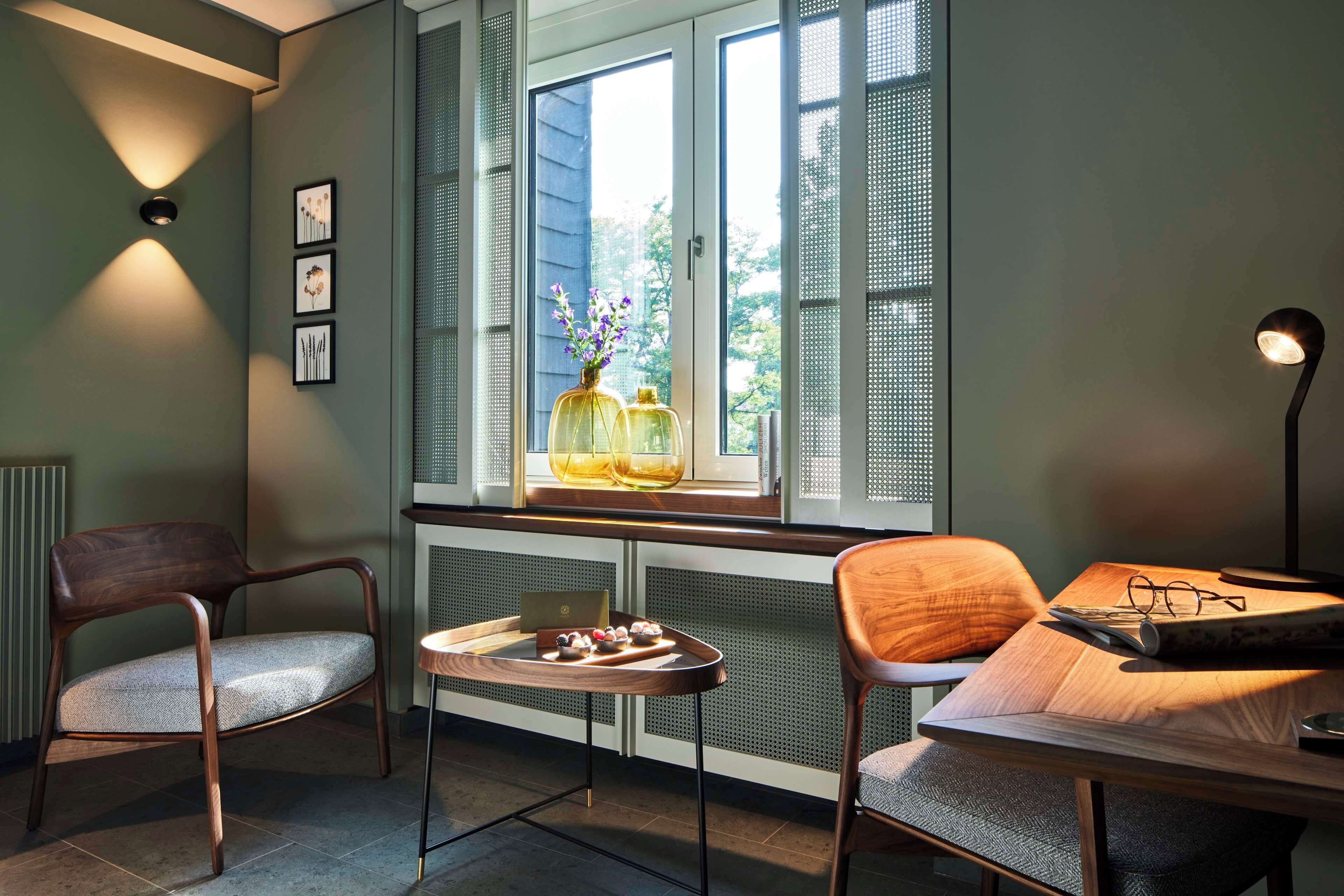 A cozy room with a wooden table, two chairs, a window with a view, and a radiator.