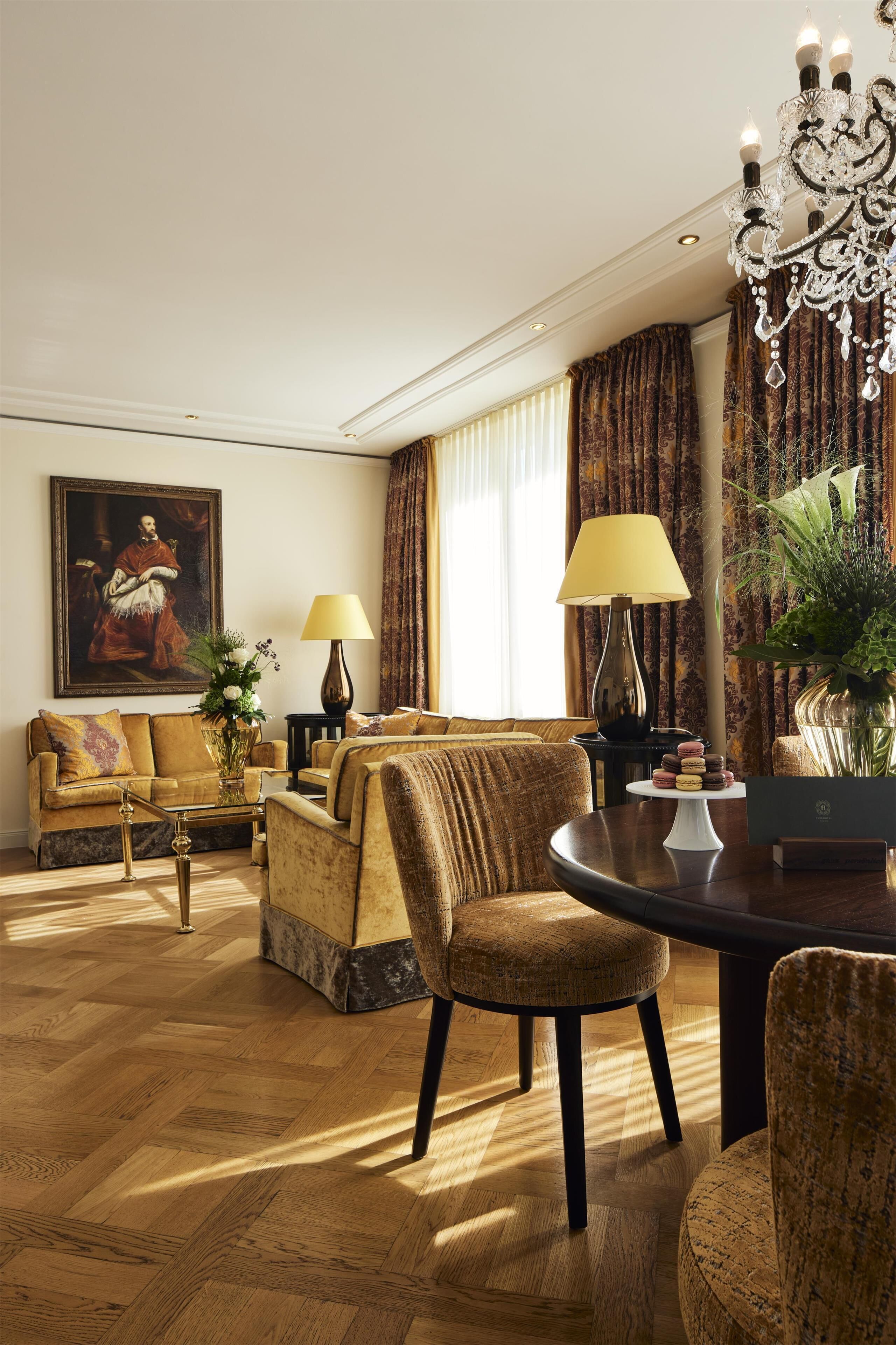 A well-lit living room with a sofa, armchairs, a coffee table, and a chandelier.