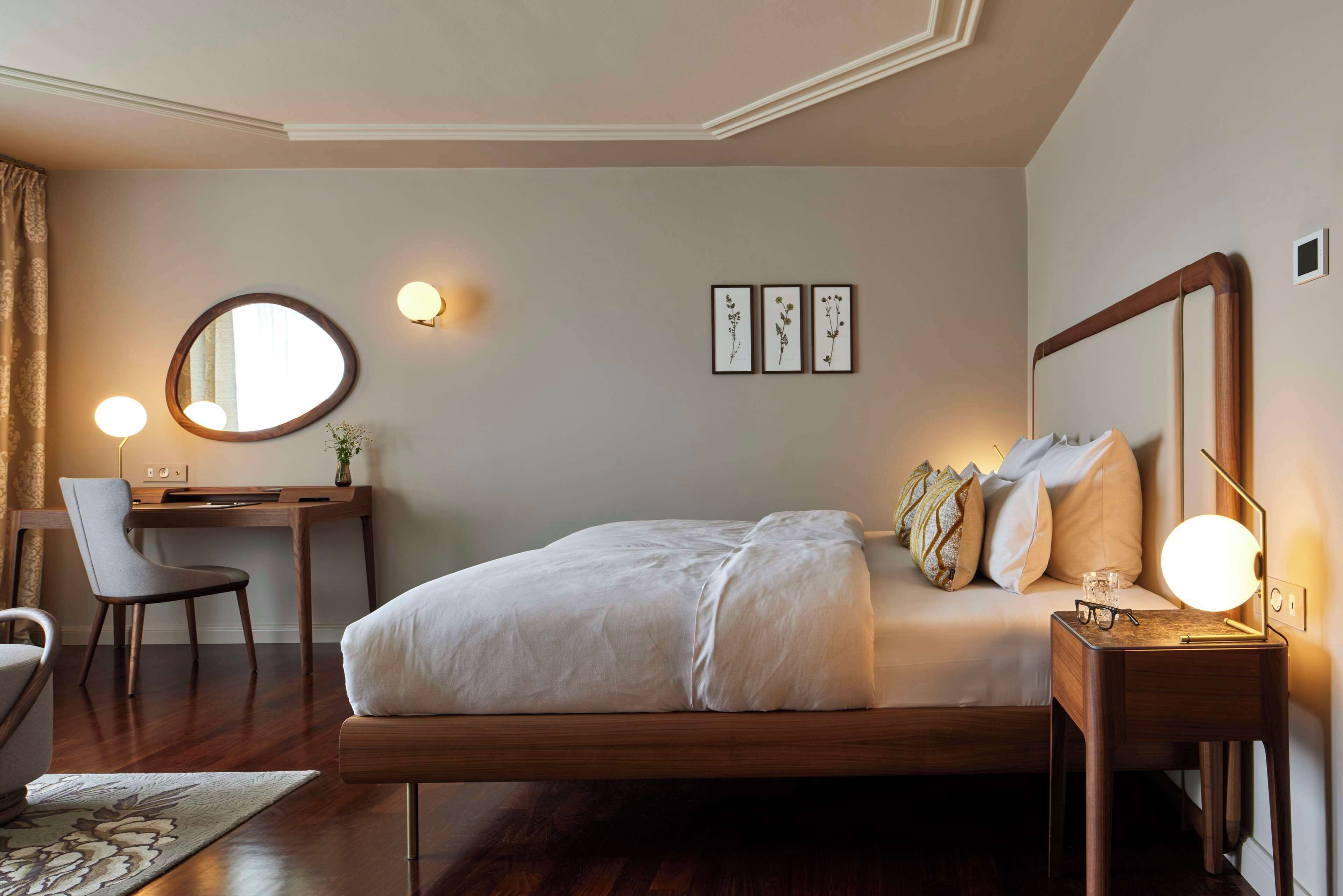 Un dormitorio con una cama de madera, un escritorio, una silla y una mesita de noche con una lámpara.