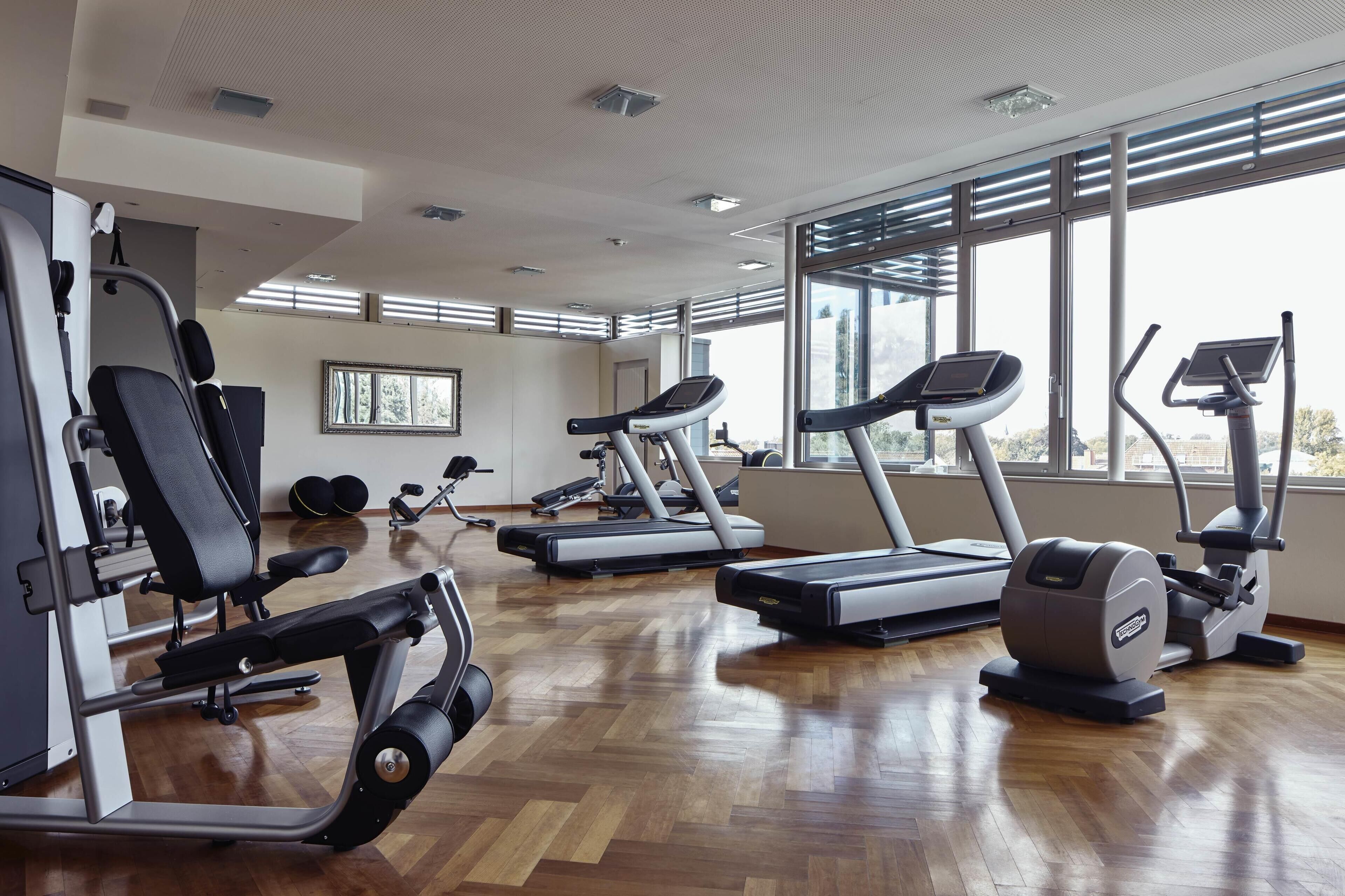 Une salle de sport équipée de tapis de course, de vélos elliptiques et de bancs de musculation.