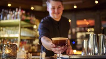 A bartender holding a cocktail glass at a bar.