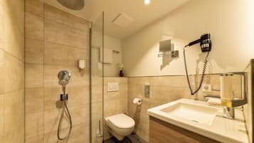 Un baño moderno con cabina de ducha de vidrio, inodoro y lavamanos con espejo.