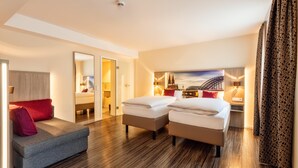 A hotel room with two beds, a sofa, a mirror, and a cityscape painting. - CityClass Hotel am Heumarkt (Cologne)