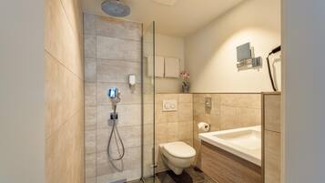 Une salle de bain moderne dotée d’une douche à parois de verre, de toilettes et d’un lavabo.