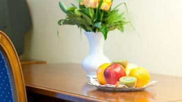 A wooden desk with a vase of flowers and a fruit bowl.