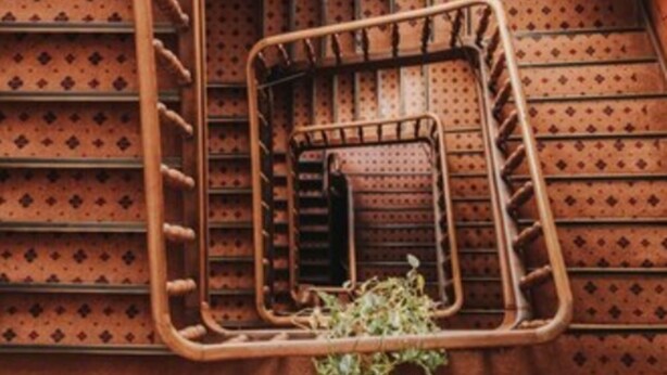 A spiral staircase with wooden balusters and metal handrails, leading to an upper floor. - Hotel Spoettel (Bad Nauheim)
