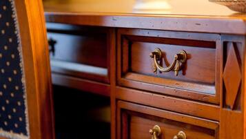 A wooden desk with two drawers and a vase with a plant on top.