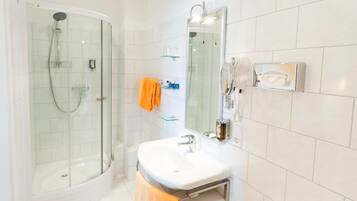 A modern bathroom with a glass-enclosed shower, a white sink, and a mirror.