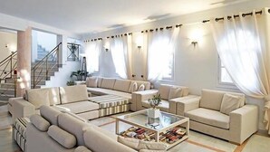 Una sala moderna con un sofá seccional, una mesa de centro con libros y una escalera al fondo.