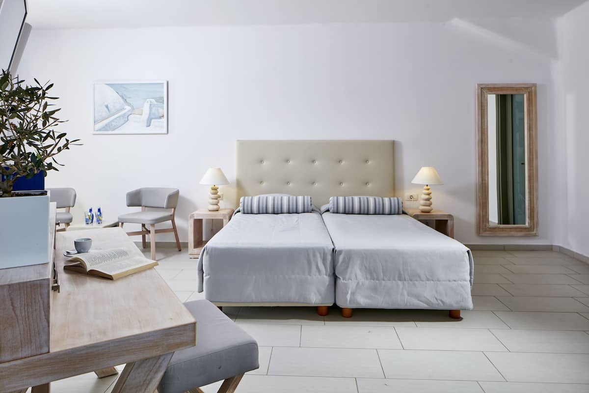 Ein modernes Schlafzimmer mit einem großen Bett, Nachttischen, einem Schreibtisch und einem Sessel.