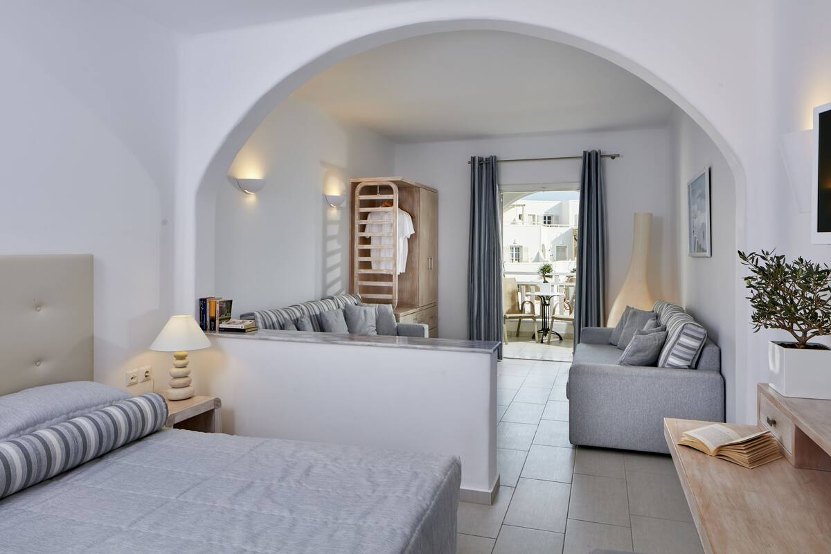 Ein modernes Hotelzimmer mit Bett, Sofa, Schreibtisch und Kleiderschrank.