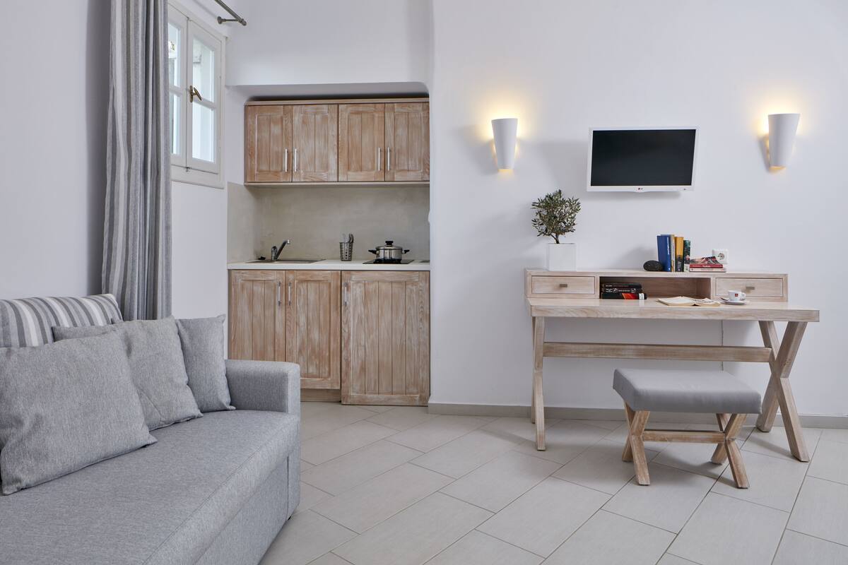 Ein modernes Wohnzimmer mit grauem Sofa, Holzkästen, einem Esstisch mit Bank und einem flachbildfernseher an der Wand.