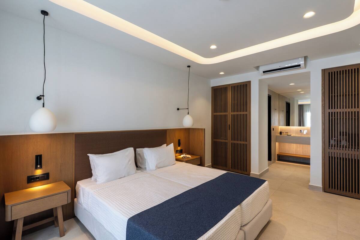 Ein modernes Hotelzimmer mit einem großen Bett, Nachttischen, einem Schrank und einem Kleiderschrank.
