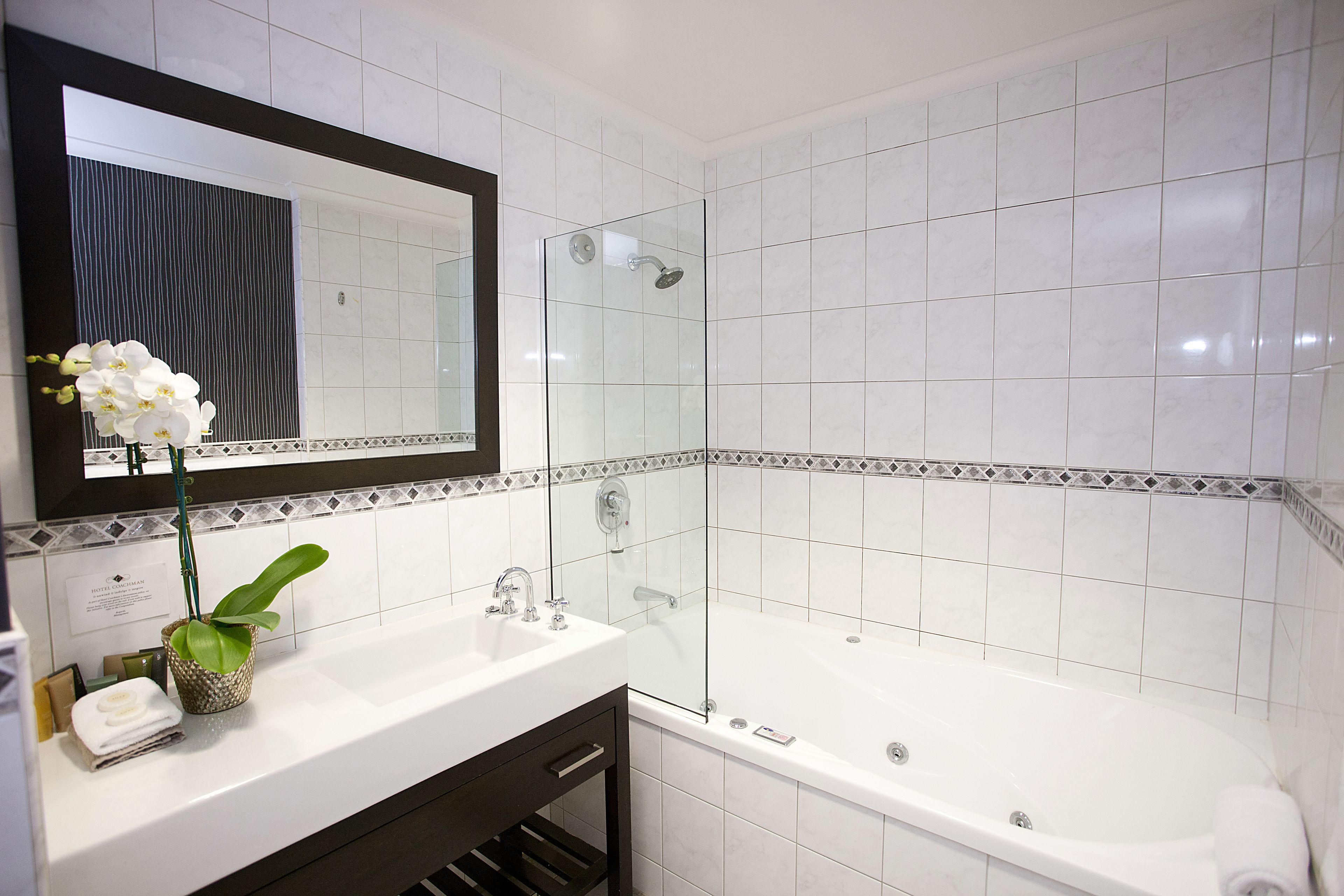 A modern bathroom with a white sink, a glass shower enclosure, and a large bathtub.