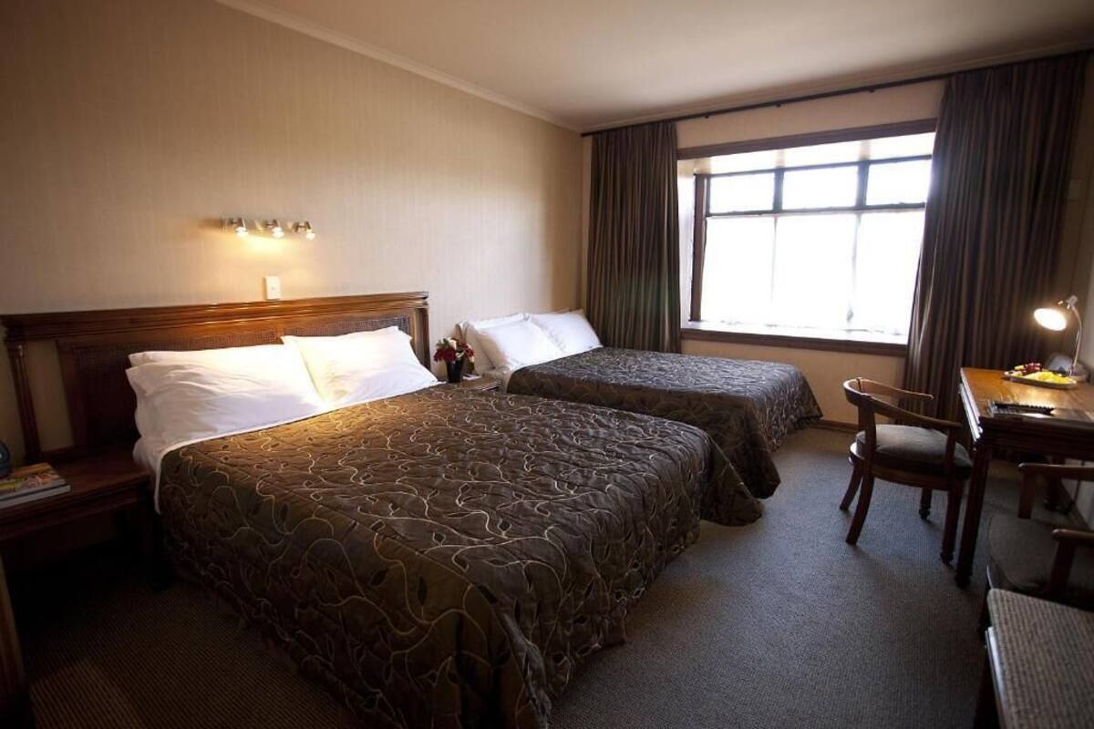 A hotel room with two beds, a desk, and a chair.