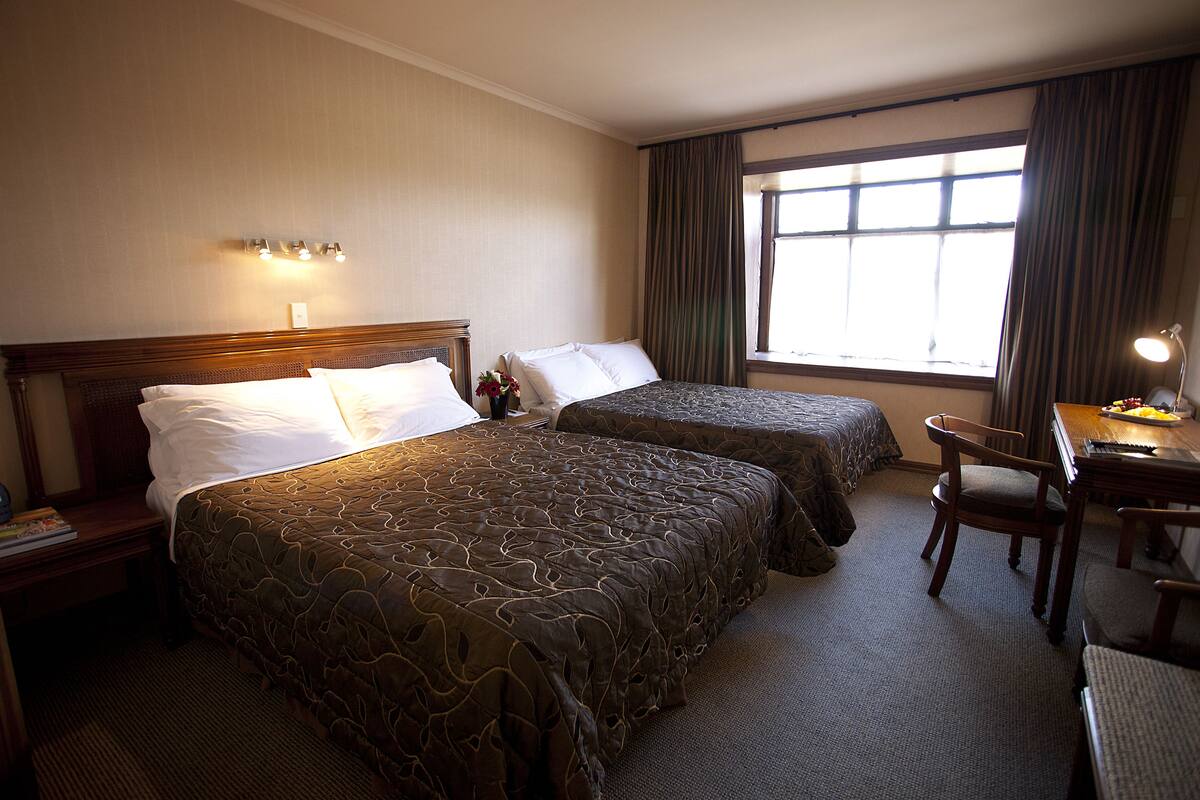 A hotel room with two beds, a desk, and a chair.