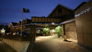 A hotel entrance with a stone facade, a sign reading "HOTEL COACHMAN," and a brick pathway leading to the entrance. - Distinction Coachman Hotel, Palmerston North (Palmerston North)