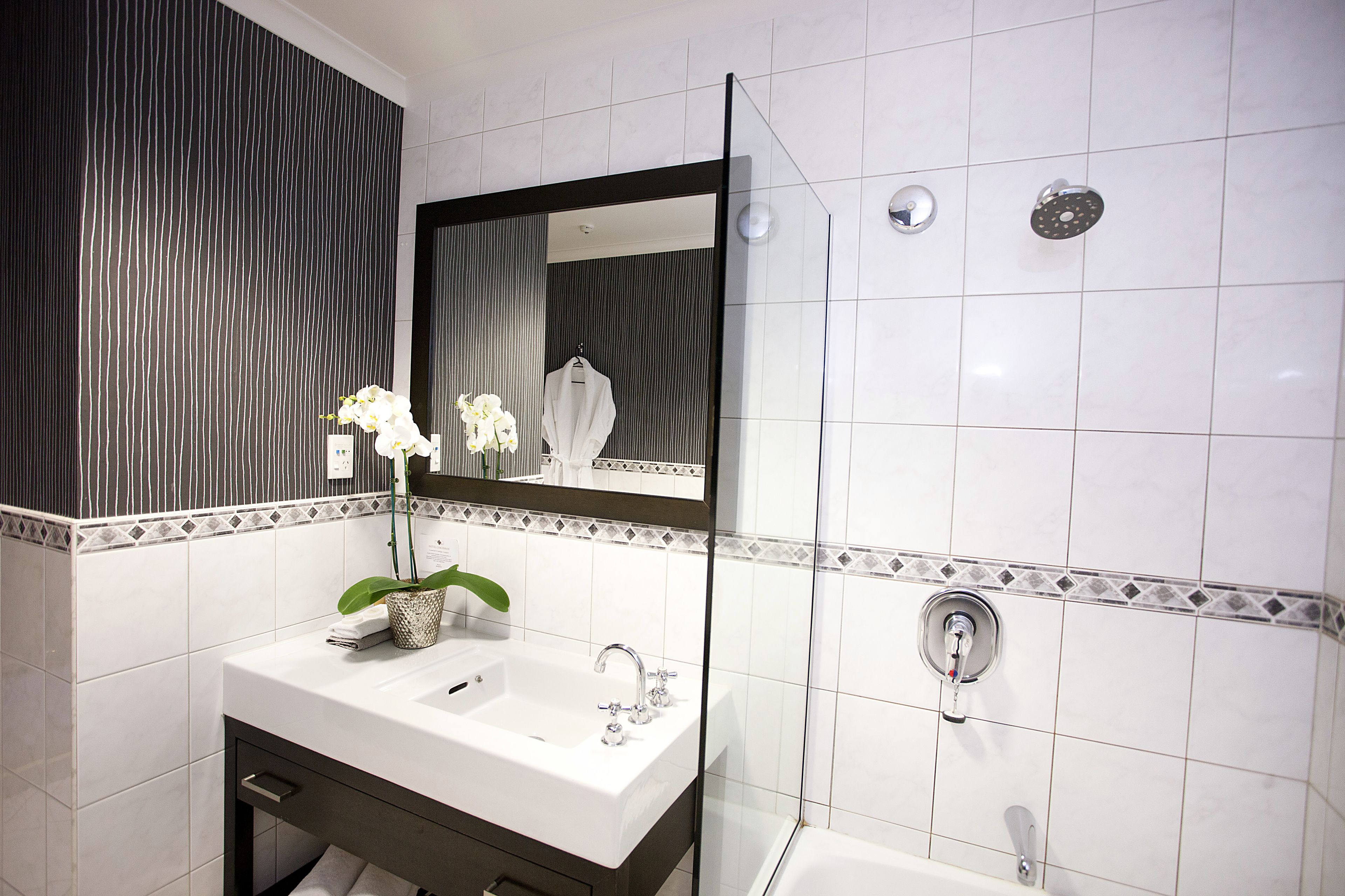 Un baño moderno con un lavamanos blanco, un espejo y una ducha.
