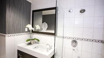 Un baño moderno con un lavamanos blanco, un espejo y una ducha.