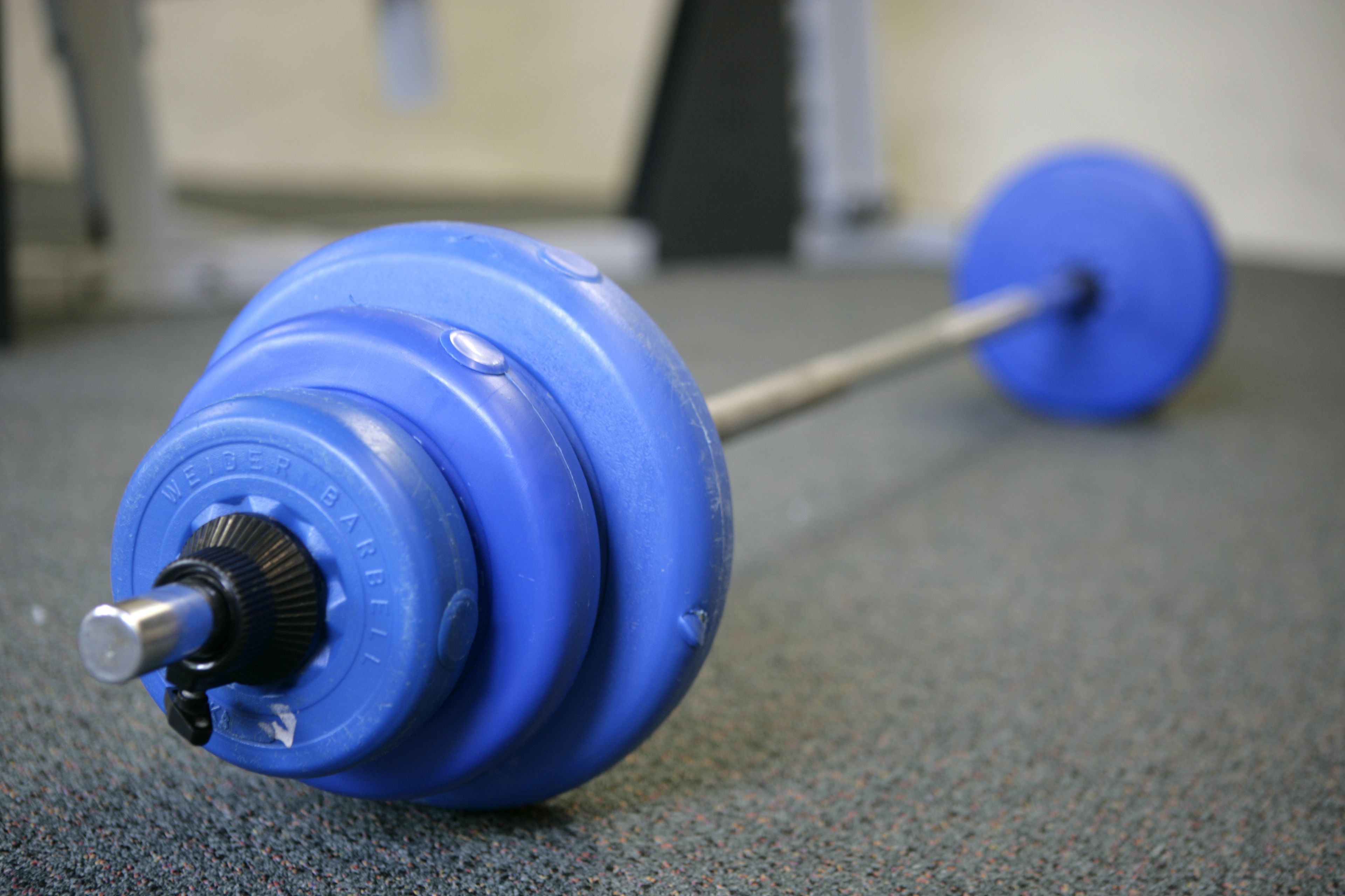 A blue weightlifting barbell with a weight plate on the floor.