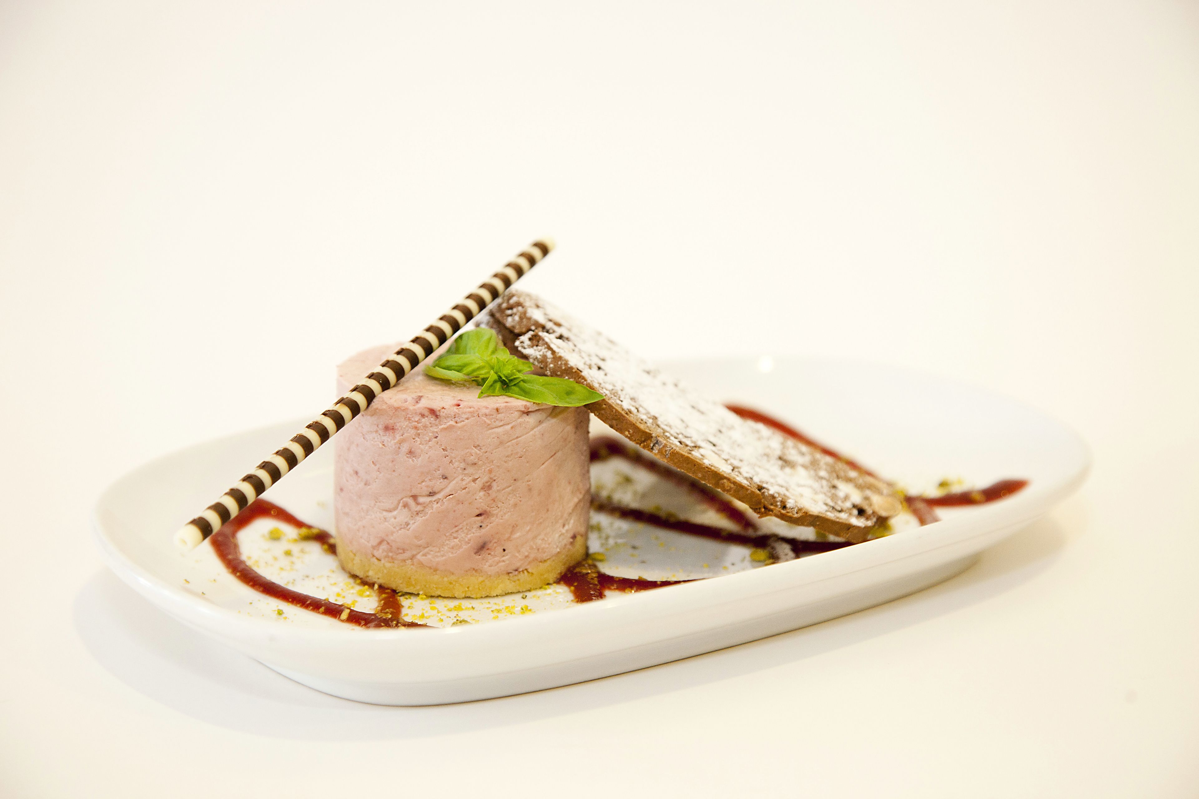 A dessert on a white plate with a striped spoon and a piece of bread.