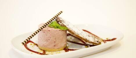 A dessert on a white plate with a striped spoon and a piece of bread.