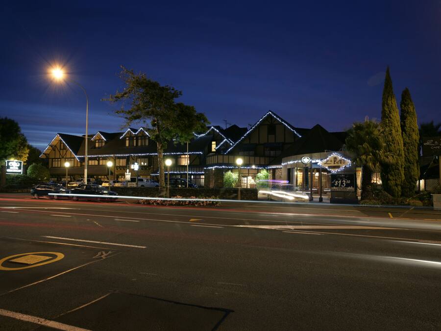A hotel with multiple buildings, a parking lot, and a street with light trails.