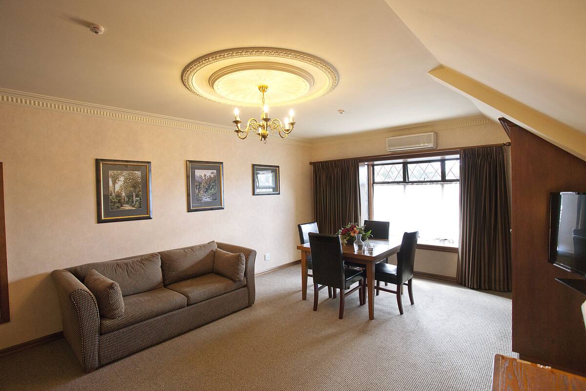 A living room with a sofa, dining table, chairs, and a chandelier.