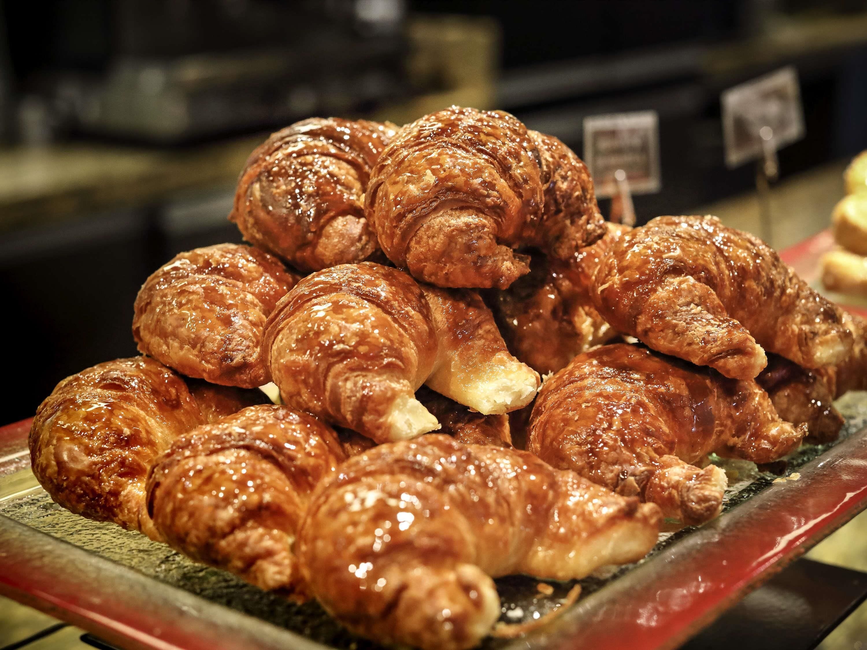 A display of golden-brown pastries, likely croissants, arranged on a tray.