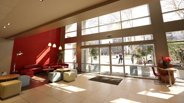 A spacious lobby with large windows, red seating, and a reception desk. - ibis Buenos Aires Congreso (Buenos Aires)