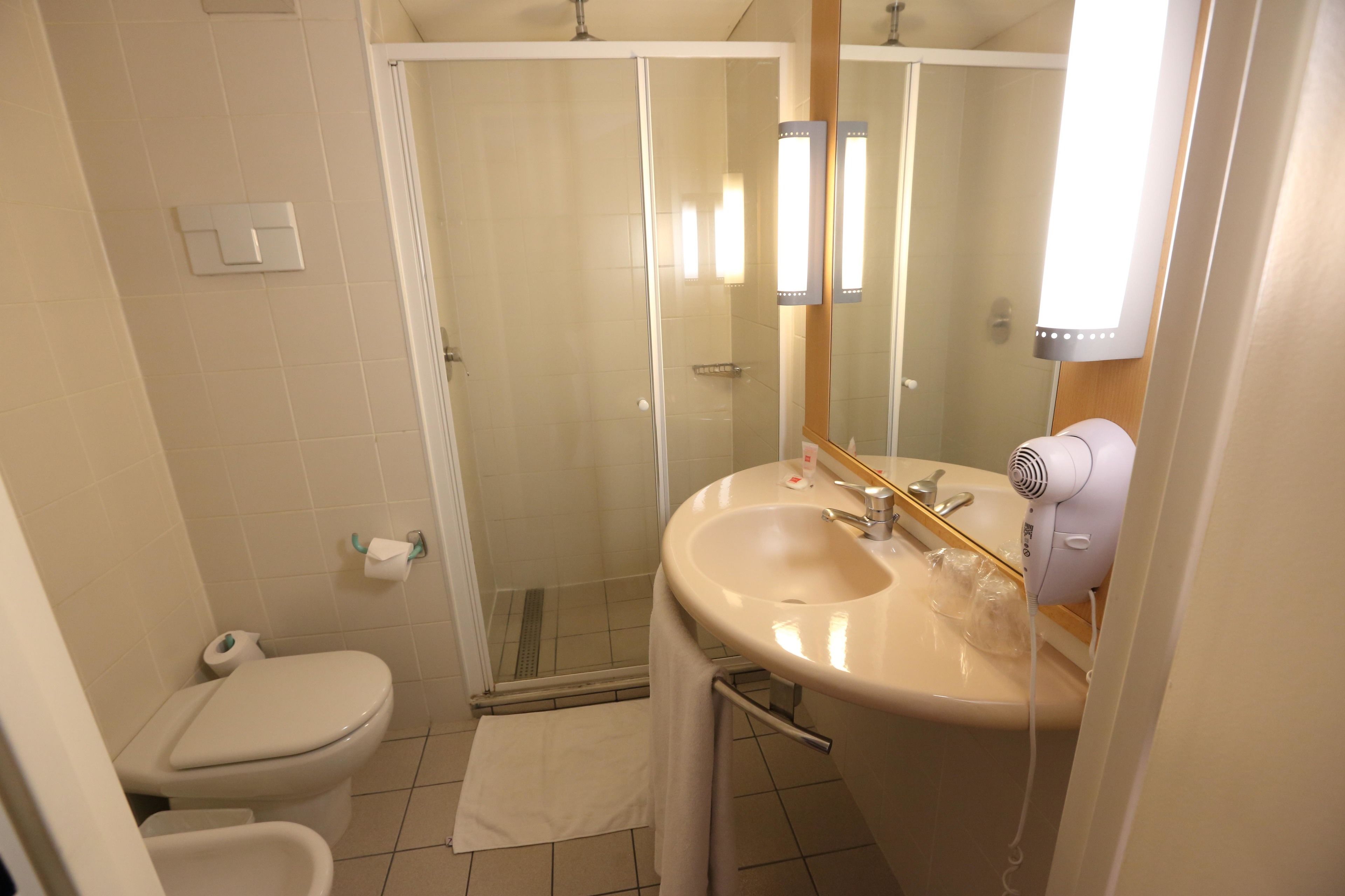 Un baño con inodoro, lavabo, espejo y ducha.