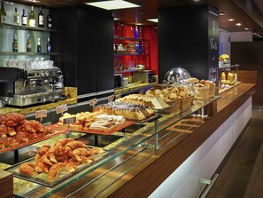 A bakery display with pastries and bread, a coffee machine, and shelves with bottles. - ibis Buenos Aires Congreso (Buenos Aires)