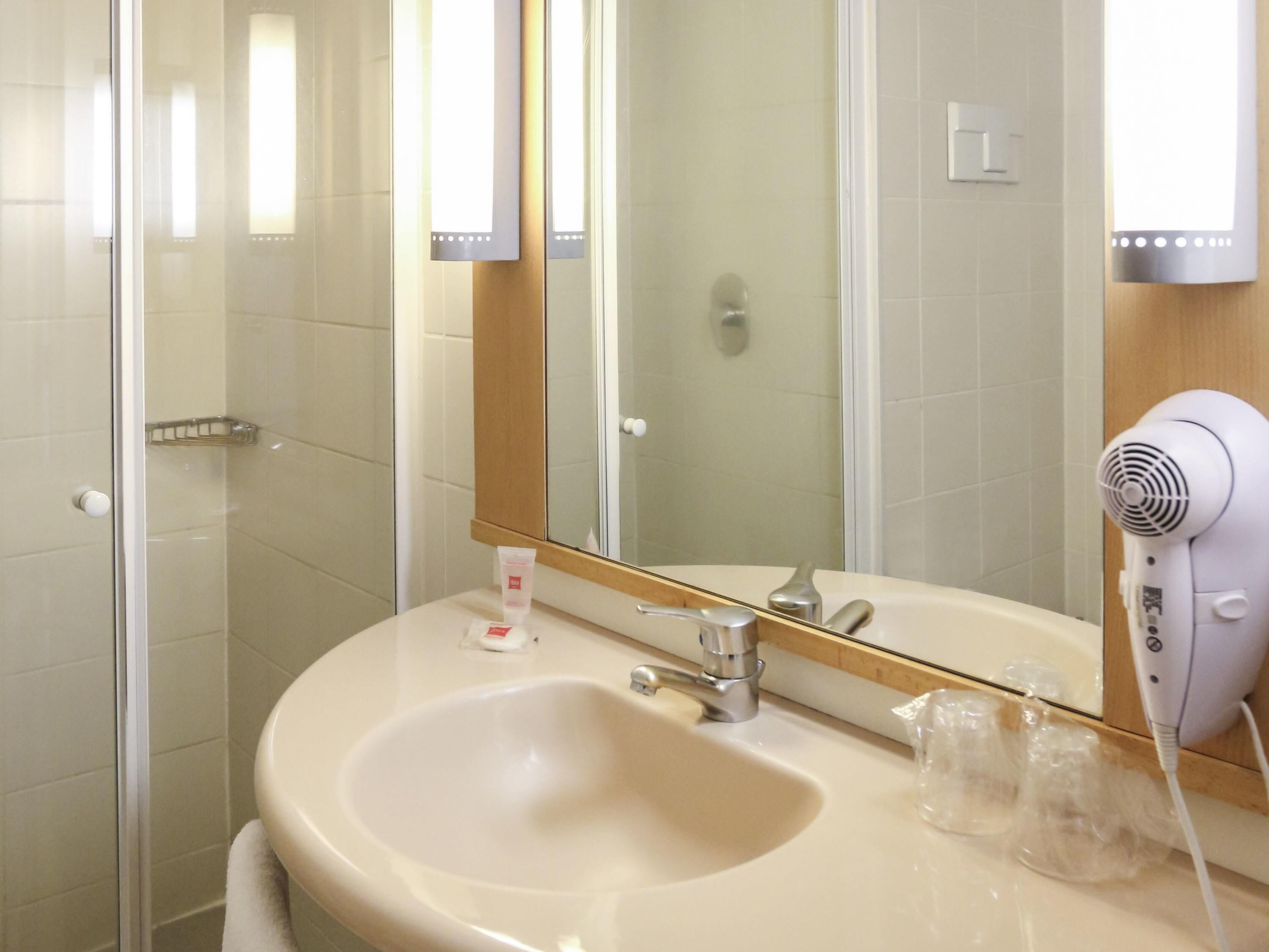 Ein Badezimmer mit Waschbecken, Spiegel und Fön.