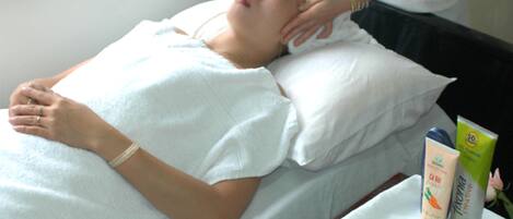 A person lying on a bed receiving a massage, with a tray of lime slices and a bottle of lotion nearby.