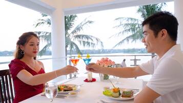 A dining table with a view of palm trees and a body of water.