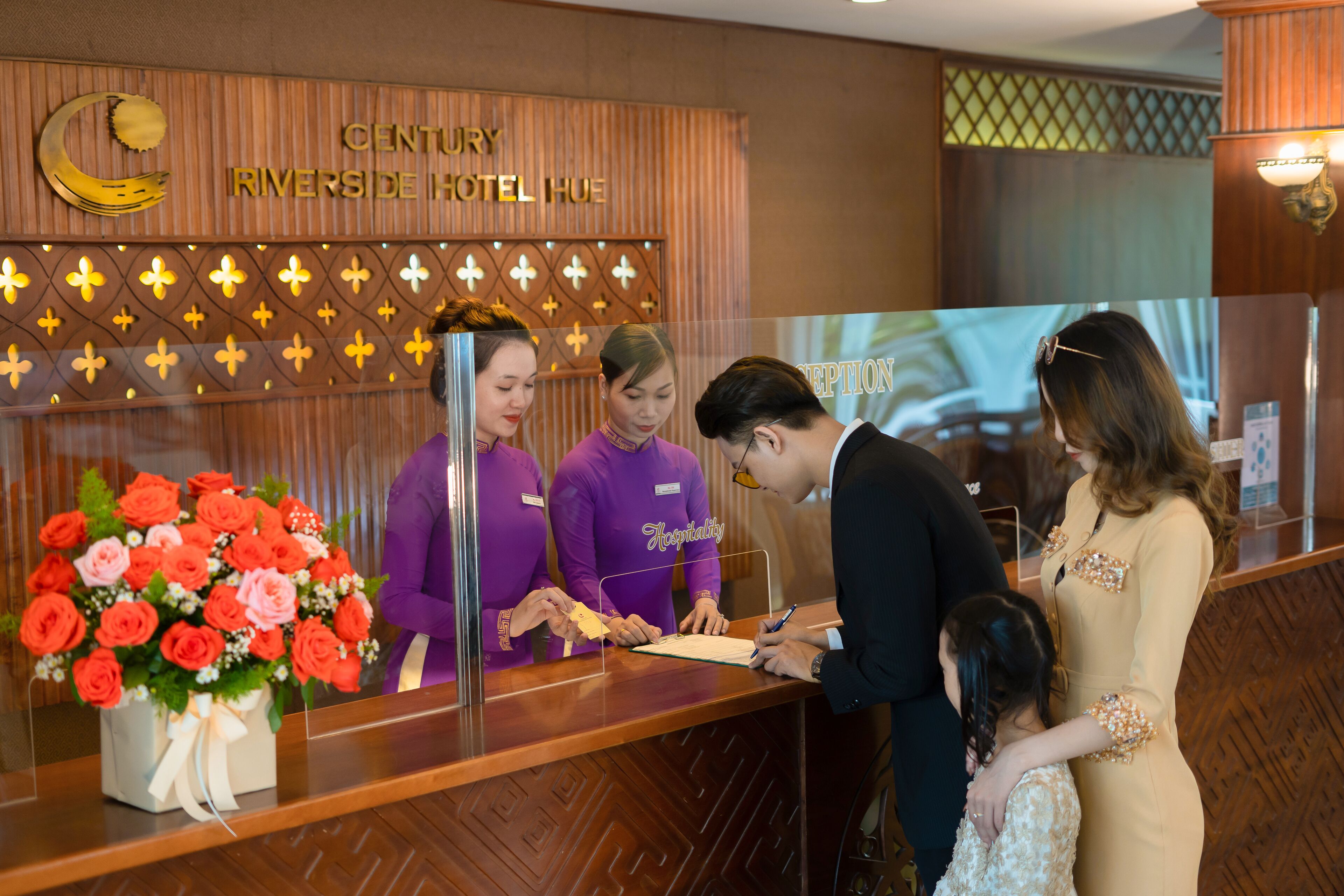 En reception på Century Riverside Hotel Hue med blomsterdekoration og et skilt over.