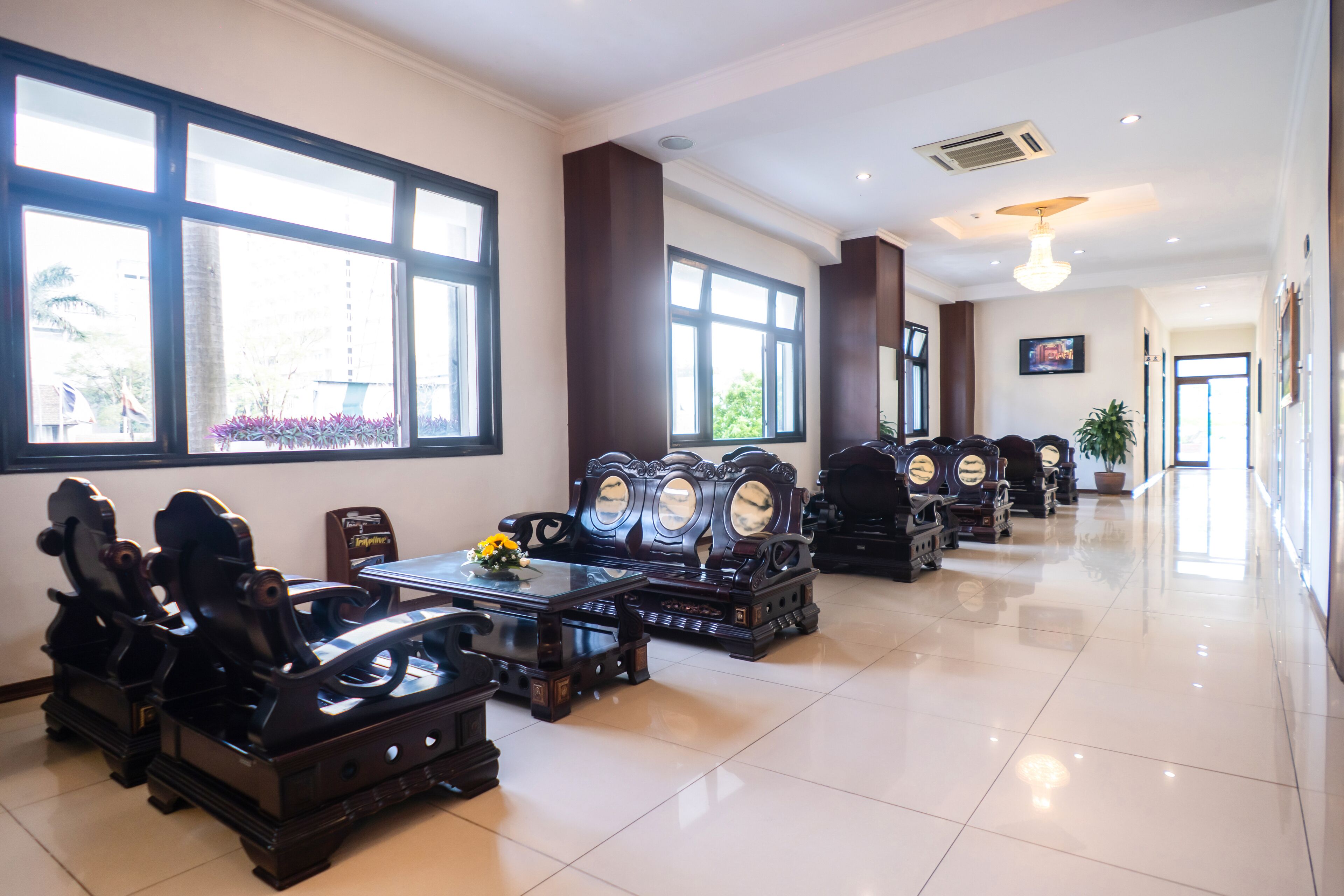 A spacious lobby with large windows, a central seating area with chairs and a table, and a potted plant.
