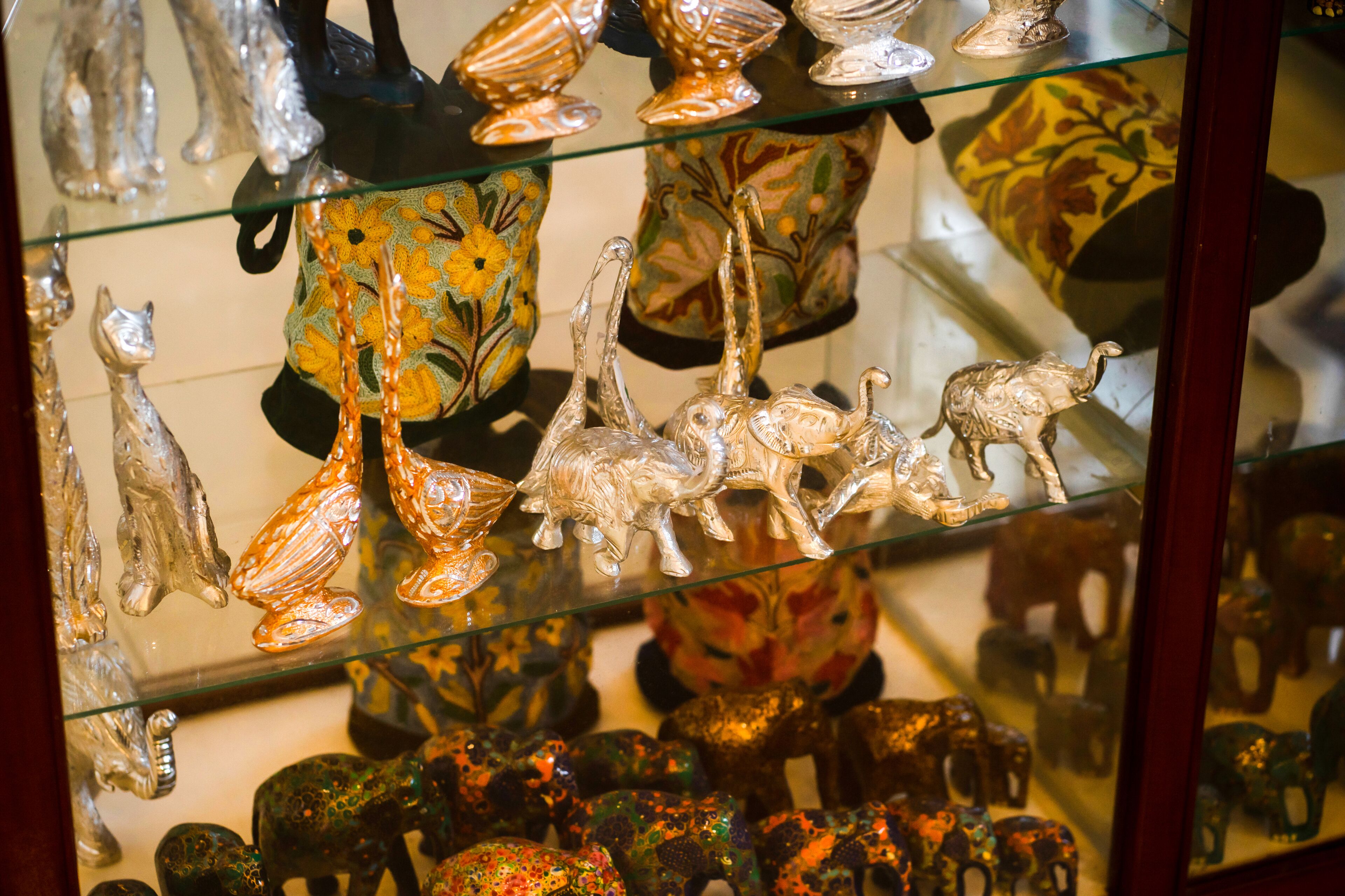 A display of glass figurines and pottery on shelves.