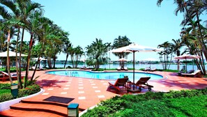 A poolside area with lounge chairs, umbrellas, and a view of the water.