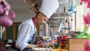A chef in a white hat and striped apron preparing food in a kitchen with a traditional stove and various dishes on the counter.