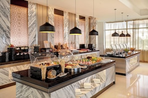 A buffet with a marble countertop, various food items, and decorative wall panels. - Holiday Inn Melaka by IHG (Malacca City)