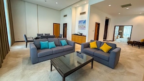 Ein geräumiger Wohnbereich mit zwei Sofas, einem Couchtisch und einer Küche im Hintergrund.