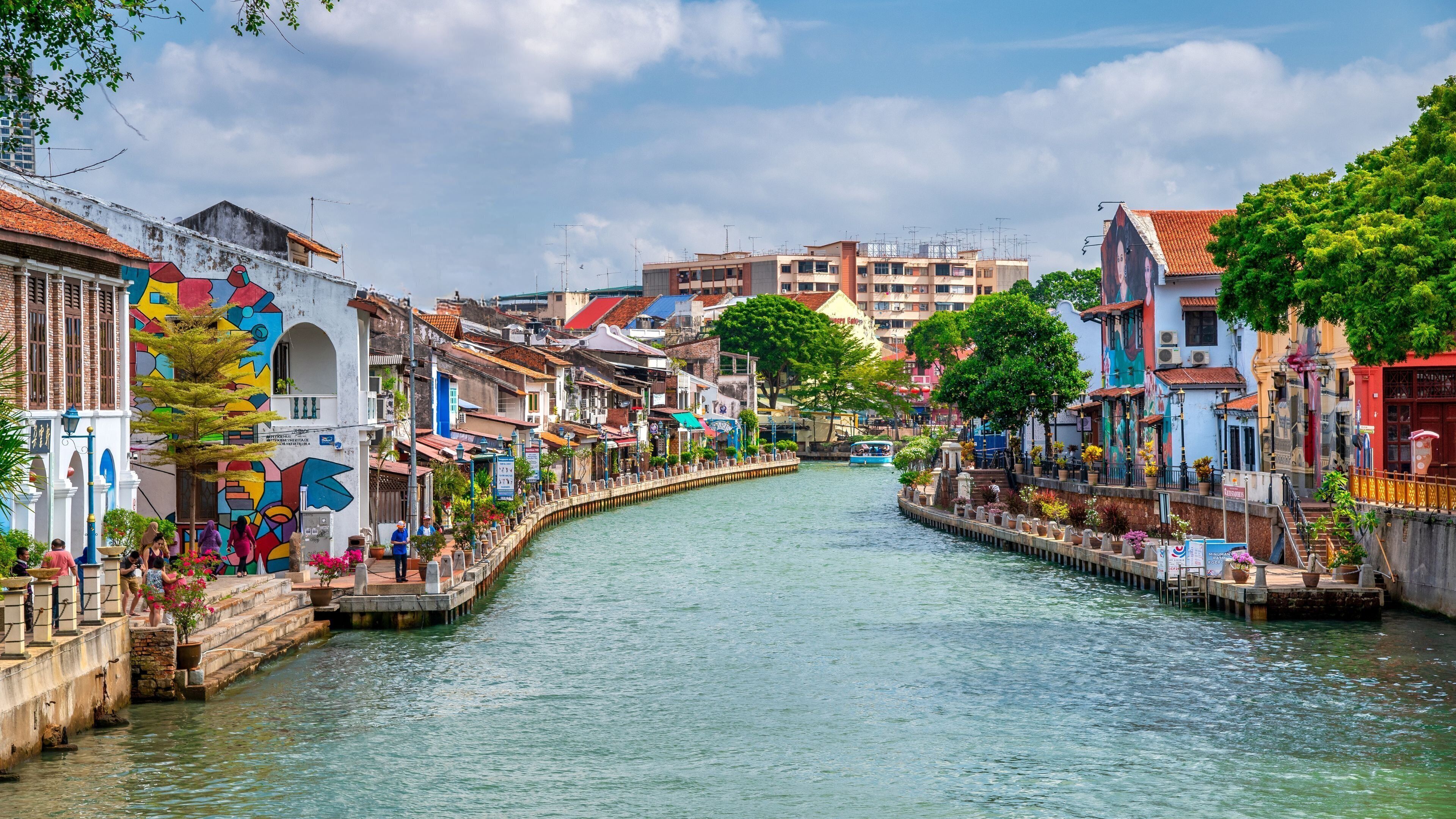 A canal lined with colorful buildings, a narrow waterway, and a bridge.