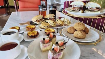A table with pastries, sandwiches, and coffee cups.