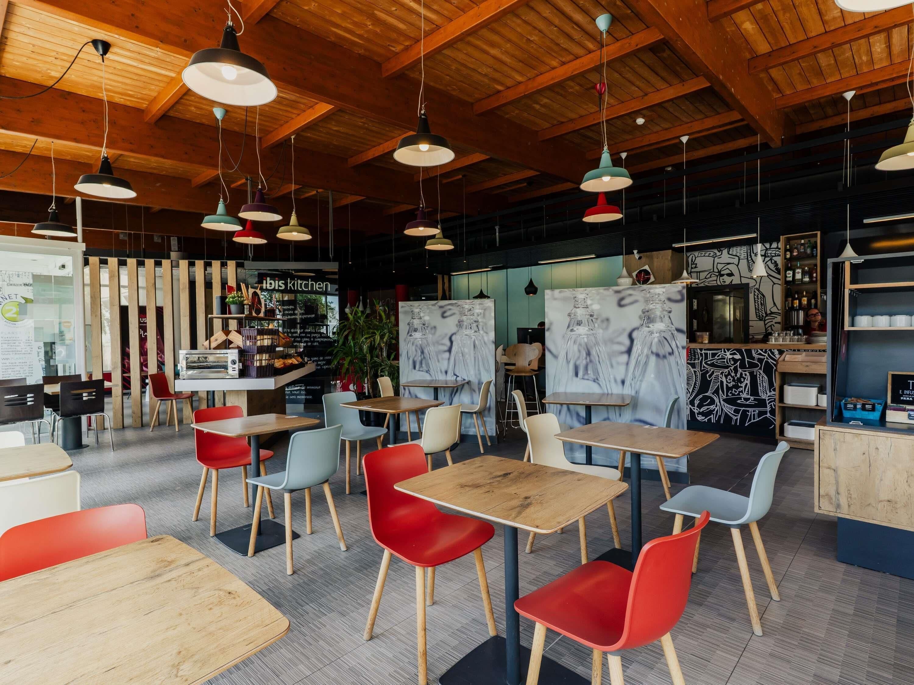 L’intérieur d’un restaurant est agrémenté de poutres en bois au plafond, de plusieurs suspensions et propose différents types de sièges, notamment des tables et des chaises.