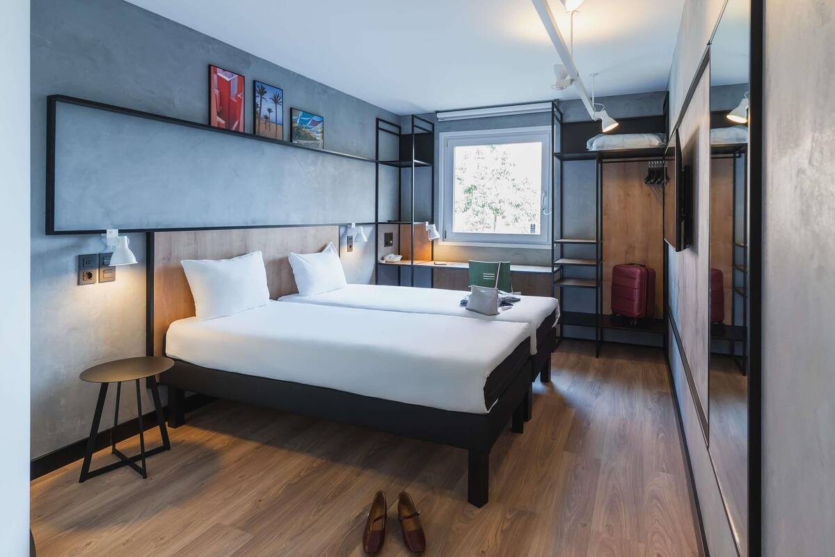 Una habitación de hotel moderna con una cama grande, mesitas de noche, un escritorio y una ventana.