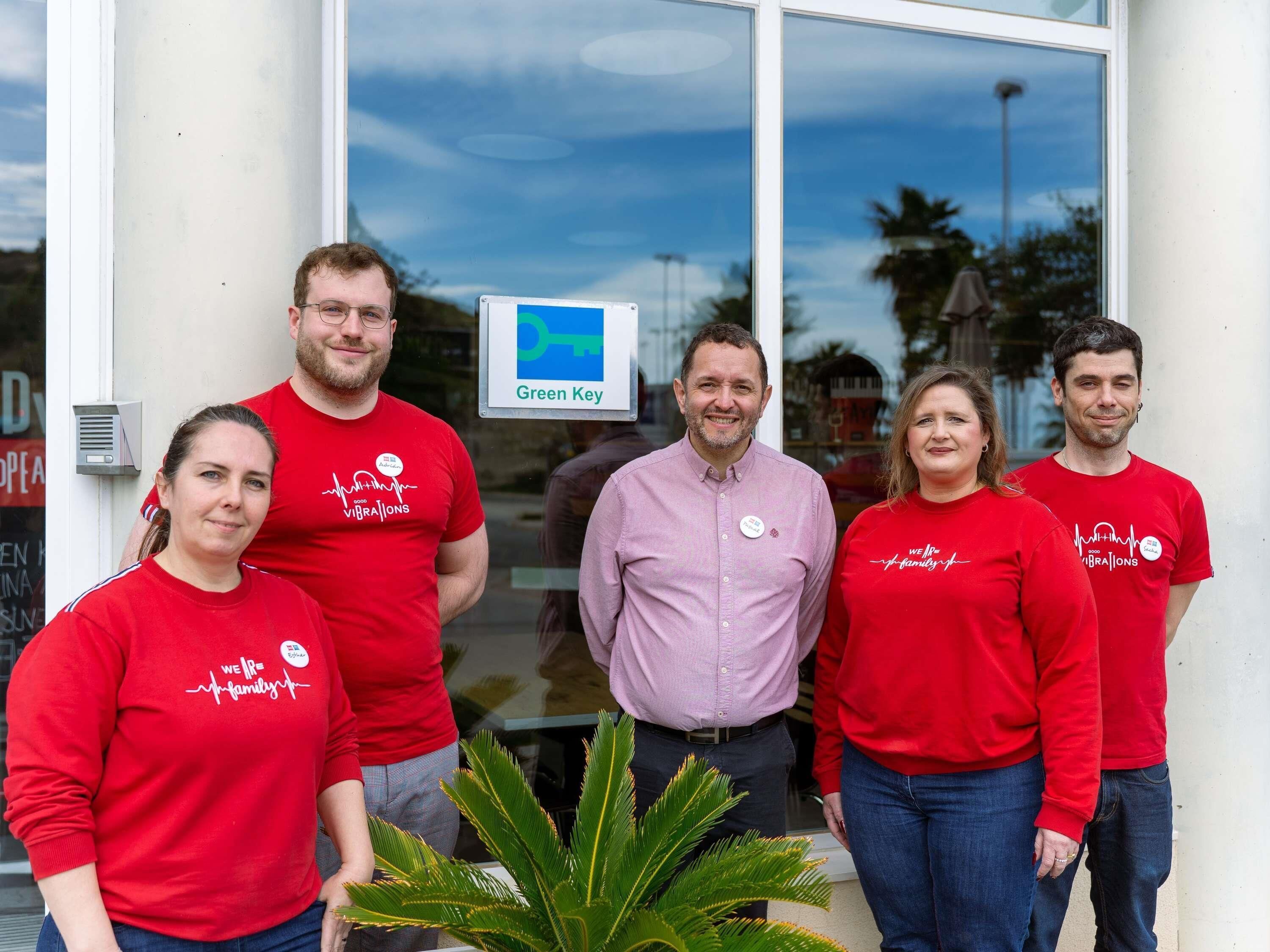 A group of people standing in front of a building with a sign that reads 'Green Key.'