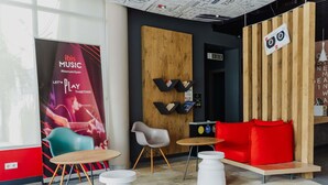 Et moderne loungeområde med en træskillevæg, en rød sofa, en turkis stol og et hvidt bord.